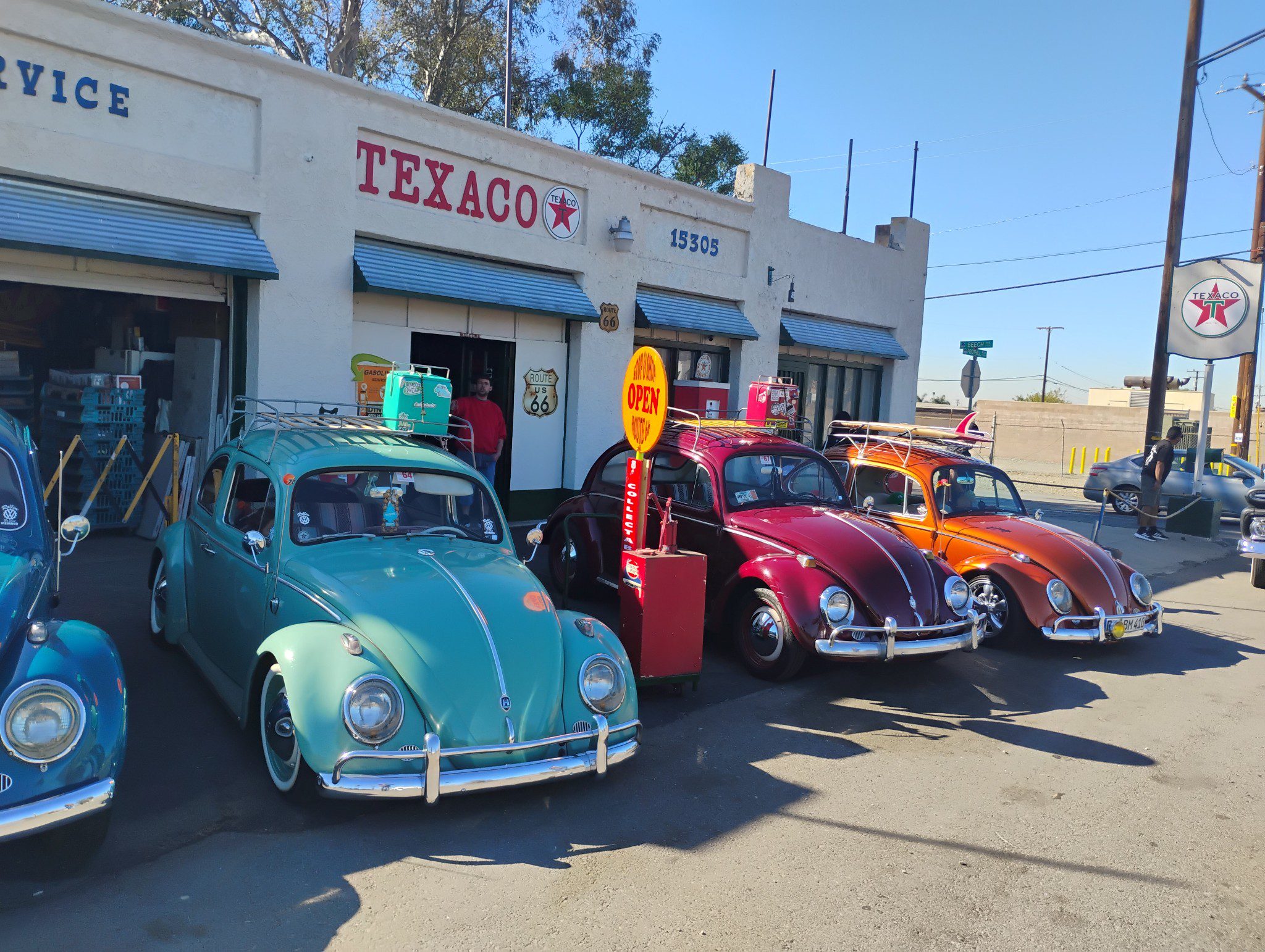 Vintage Volkswagen Beetles parked outside a Texaco gas station.