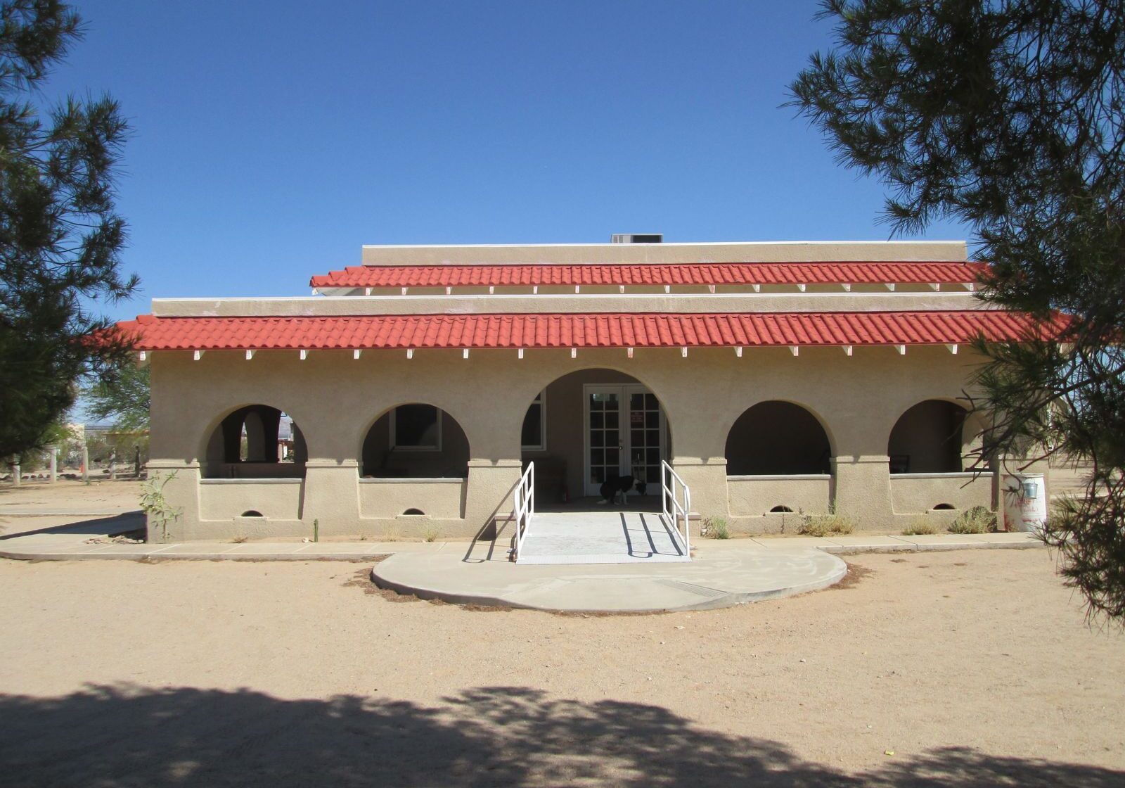 Historic building with arched windows and red-tiled roof under a clear sky.