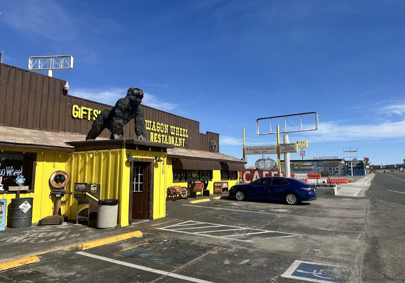 Exterior of a quirky cafe with a statue and bright yellow facade.