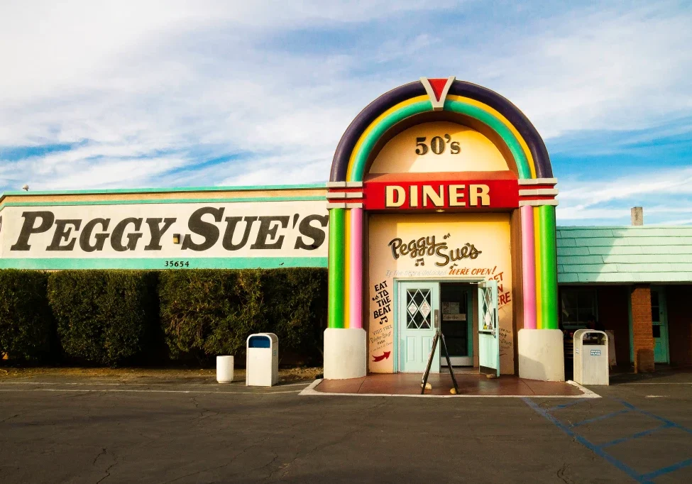Colorful 50's style diner with retro signage under a blue sky.