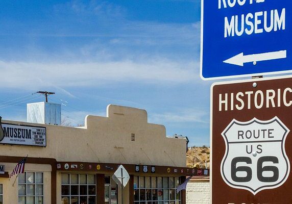 Historic Route 66 sign above a southwestern-style building under a clear blue sky.
