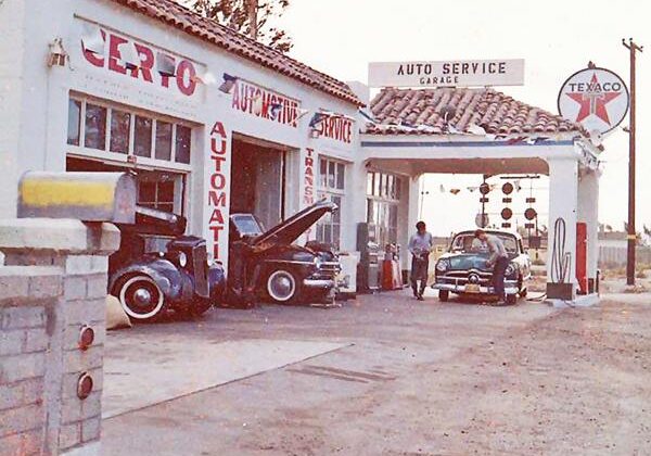 Vintage Texaco gas station with classic cars and old signage.