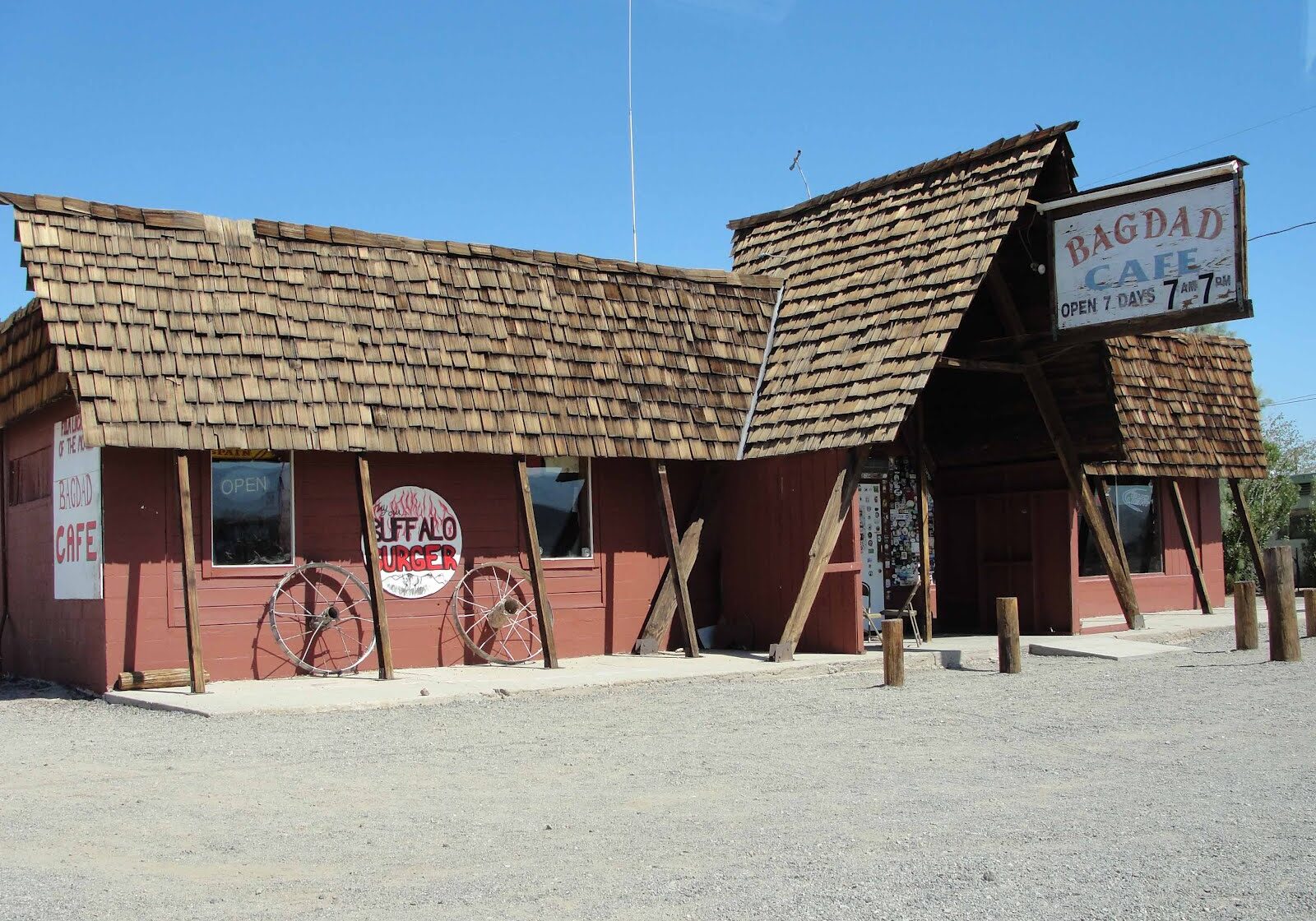 Rustic building with wooden roof and faded signs in a dry, sunny area.