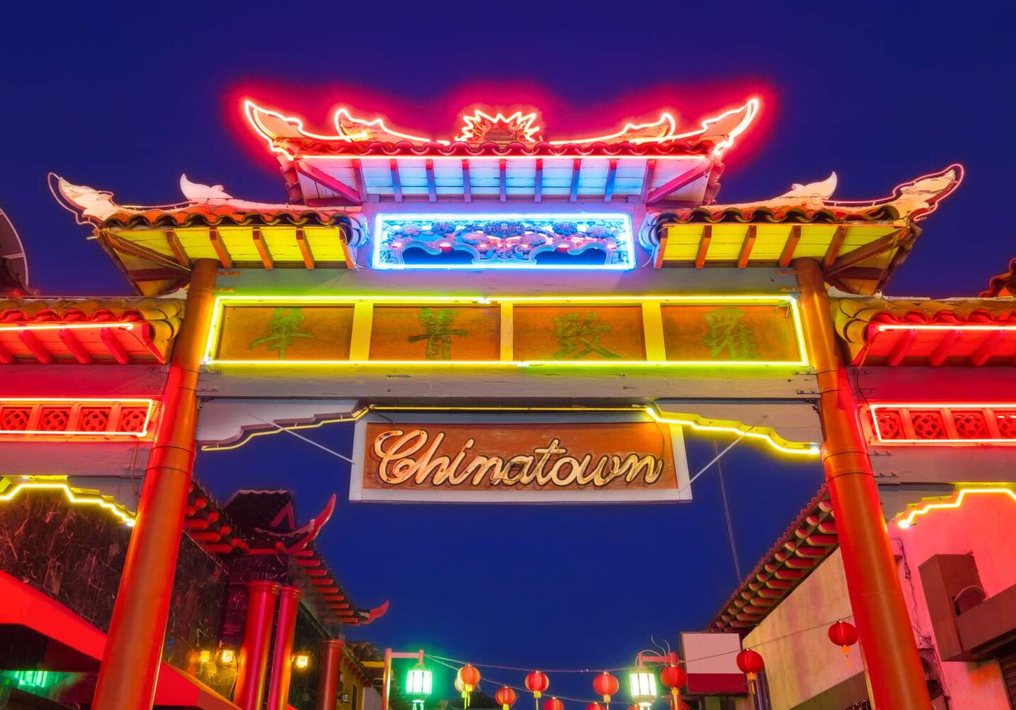 Illuminated Chinatown gate glowing against night sky.