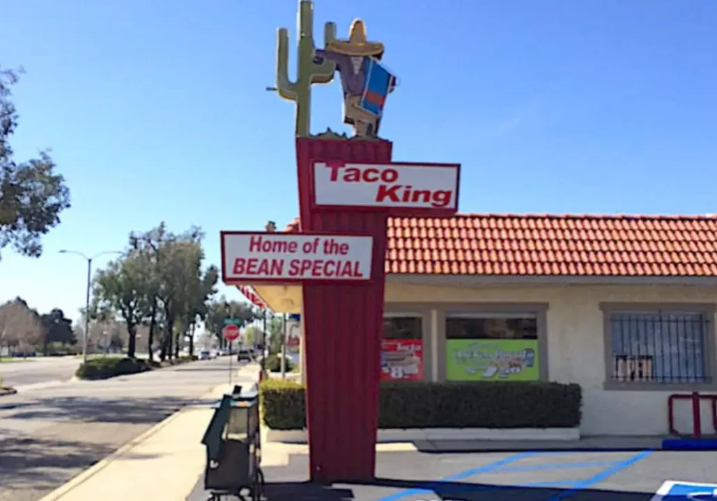 A Taco King sign advertising the 'Bean Special' with a cowboy figure on top.