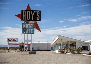 Vintage Roy's Motel and Cafe sign against a clear blue sky.